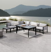 Moderne loungemeubels op een terras met uitzicht op het meer, bestaande uit een hoekbank, een tuintafel en een bijzettafel, gezien vanaf de voorkant.