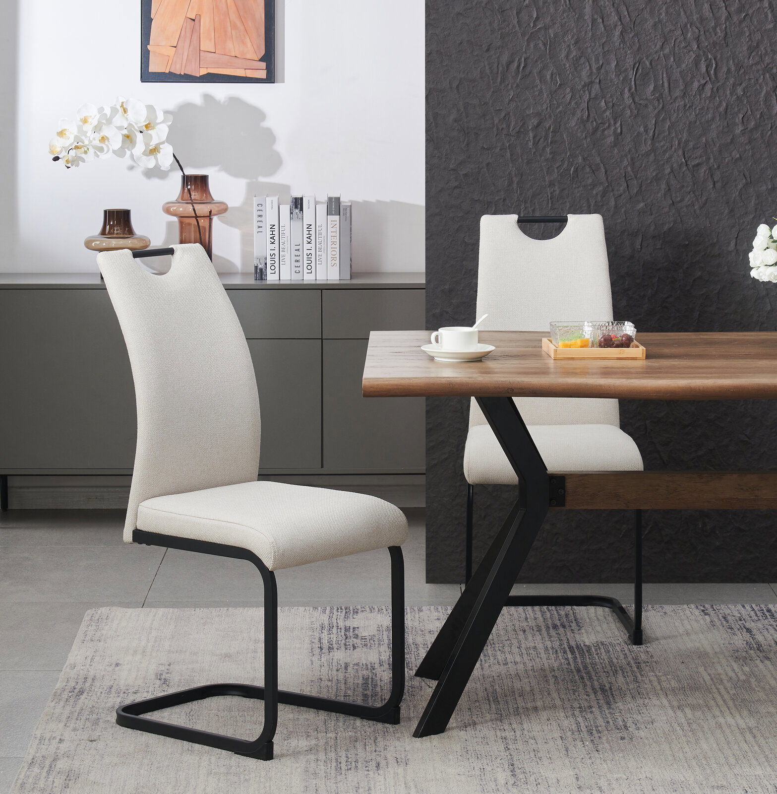Moderner Esszimmerstuhl mit hellbeigem Stoffbezug und schwarzem Metall-Schwinggestell am Holzesstisch, seitliche Perspektive im Wohnambiente