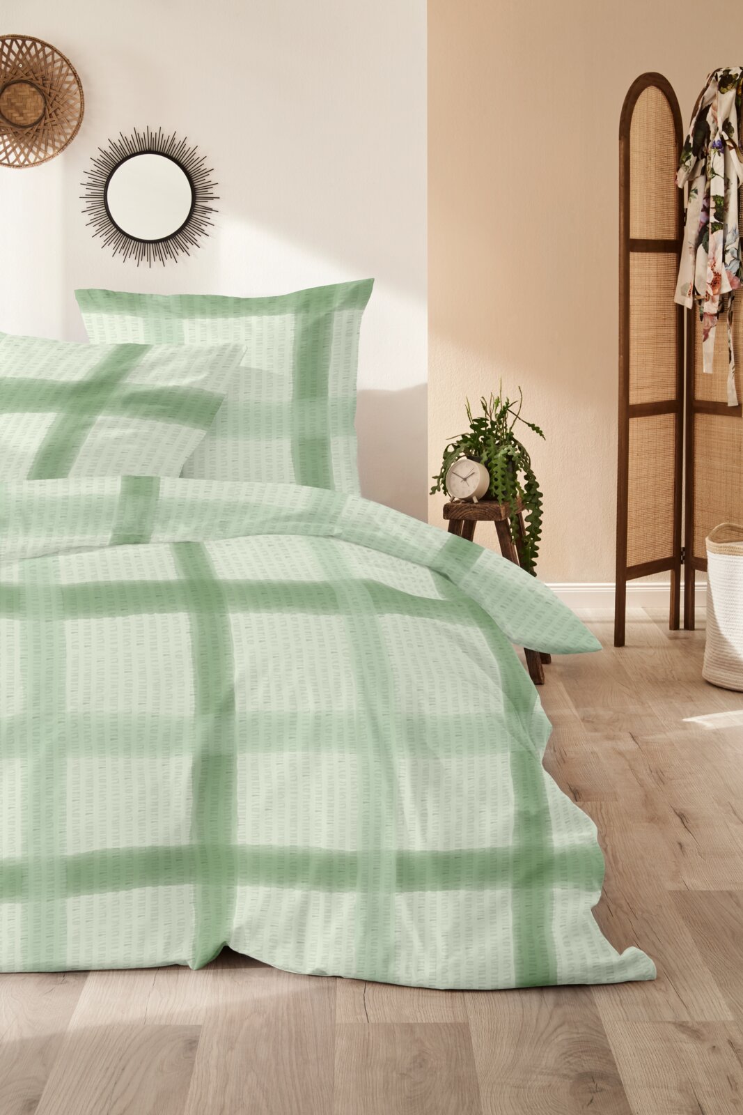Beddengoed met een groot ruitpatroon in mintgroen en wit, opgemaakt op een bed in de slaapkamer, gefotografeerd vanuit een licht schuin perspectief van voren.