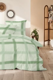 Beddengoed met een groot ruitpatroon in mintgroen en wit, opgemaakt op een bed in de slaapkamer, gefotografeerd vanuit een licht schuin perspectief van voren.
