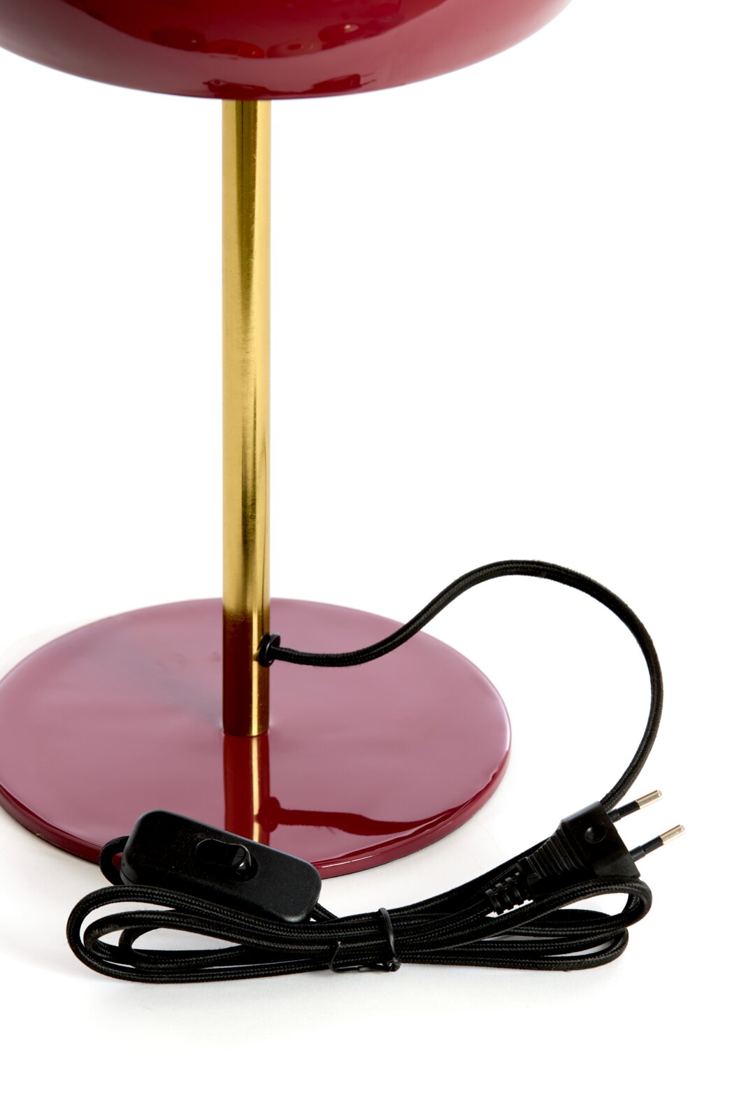 Close-up van de SURIN-tafellamp met een gouden voet en een rode sokkel, inclusief zwarte kabel en schakelaar.