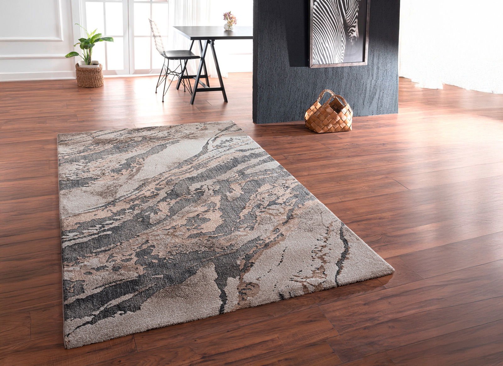 Moderner Webteppich mit abstraktem Muster in Erdtönen, perspektivisch von der Seite fotografiert.