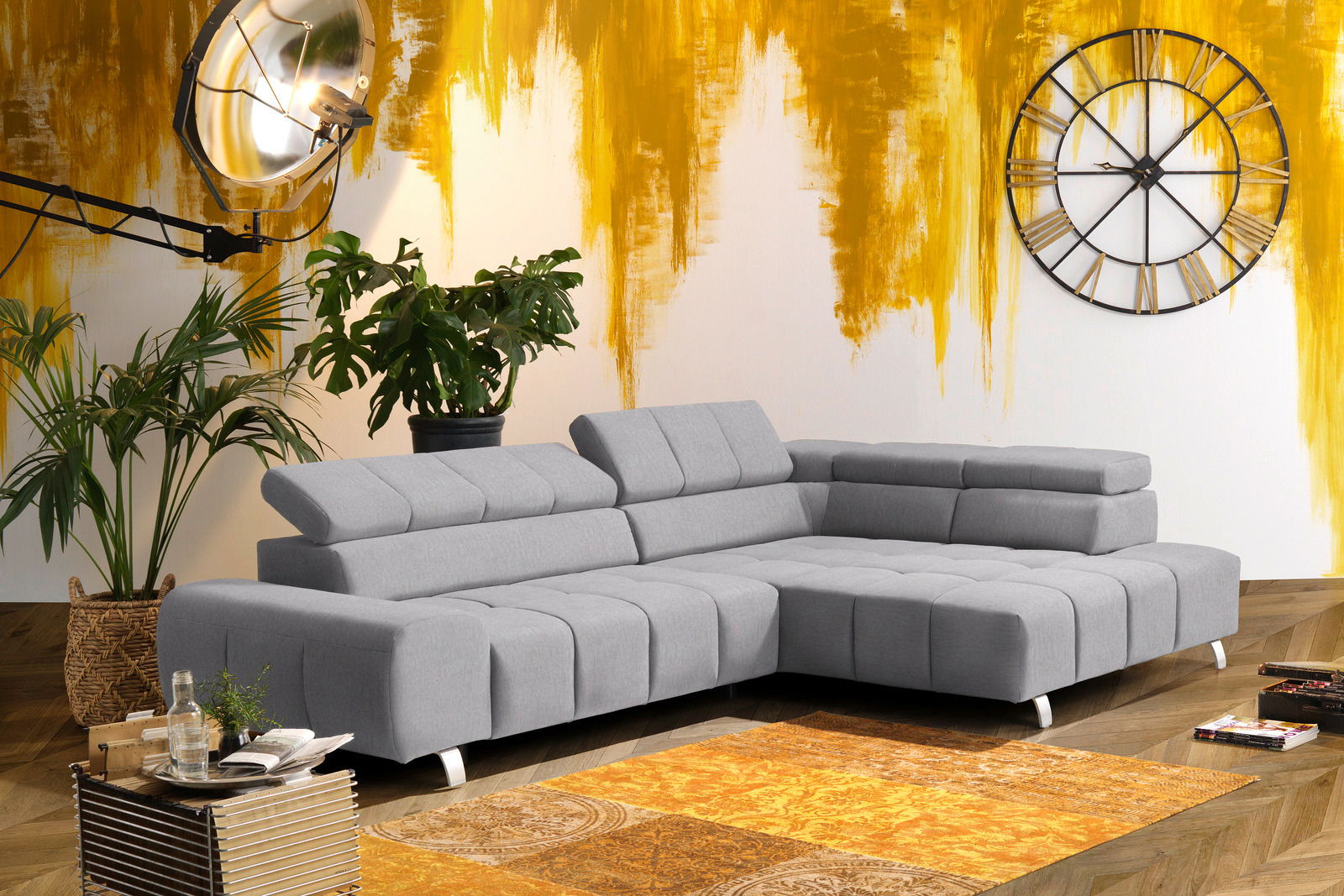 Graues Ecksofa mit Ottomane rechts, moderne Wohnzimmerumgebung, Blick von vorne.