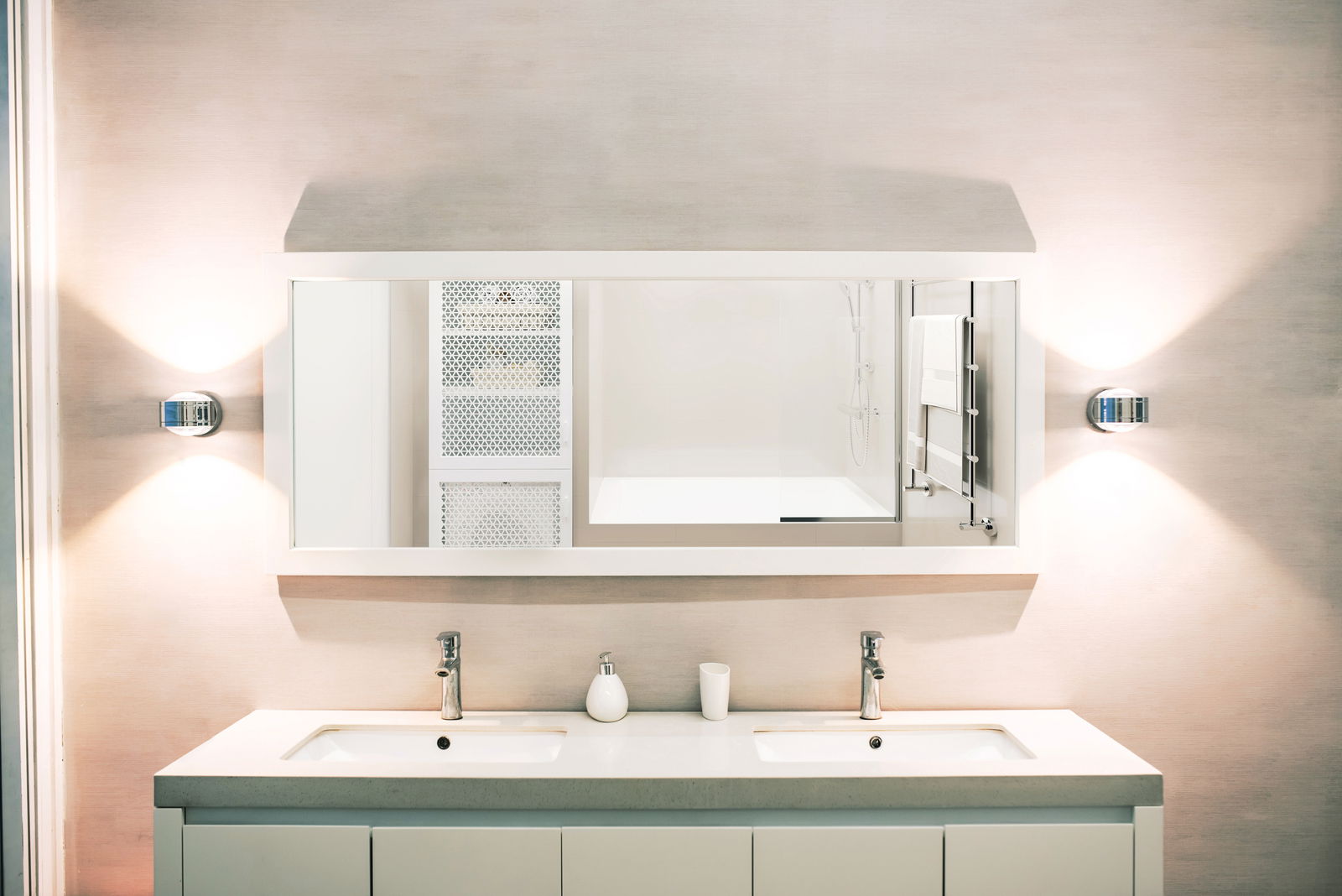 Moderne LED-Wandleuchte DUE PUNTO - UP & DOWN, installiert neben einem großen Spiegel in einem stilvollen Badezimmer, mit gleichmäßiger Beleuchtung nach oben und unten.