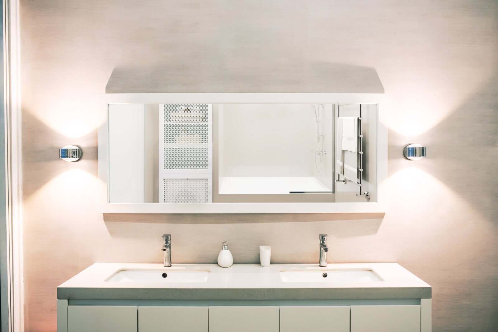 Moderne LED-Wandleuchte DUE PUNTO - UP & DOWN, installiert neben einem großen Spiegel in einem stilvollen Badezimmer, mit gleichmäßiger Beleuchtung nach oben und unten.