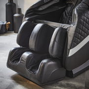 Nahaufnahme eines luxuriösen Massagesessels in schwarzem Leder mit Fuß- und Beinmassagefunktion, seitliche Perspektive.