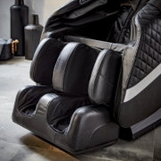 Close-up van een luxe massagestoel in zwart leer met voet- en beenmassagefunctie, gezien vanaf de zijkant.