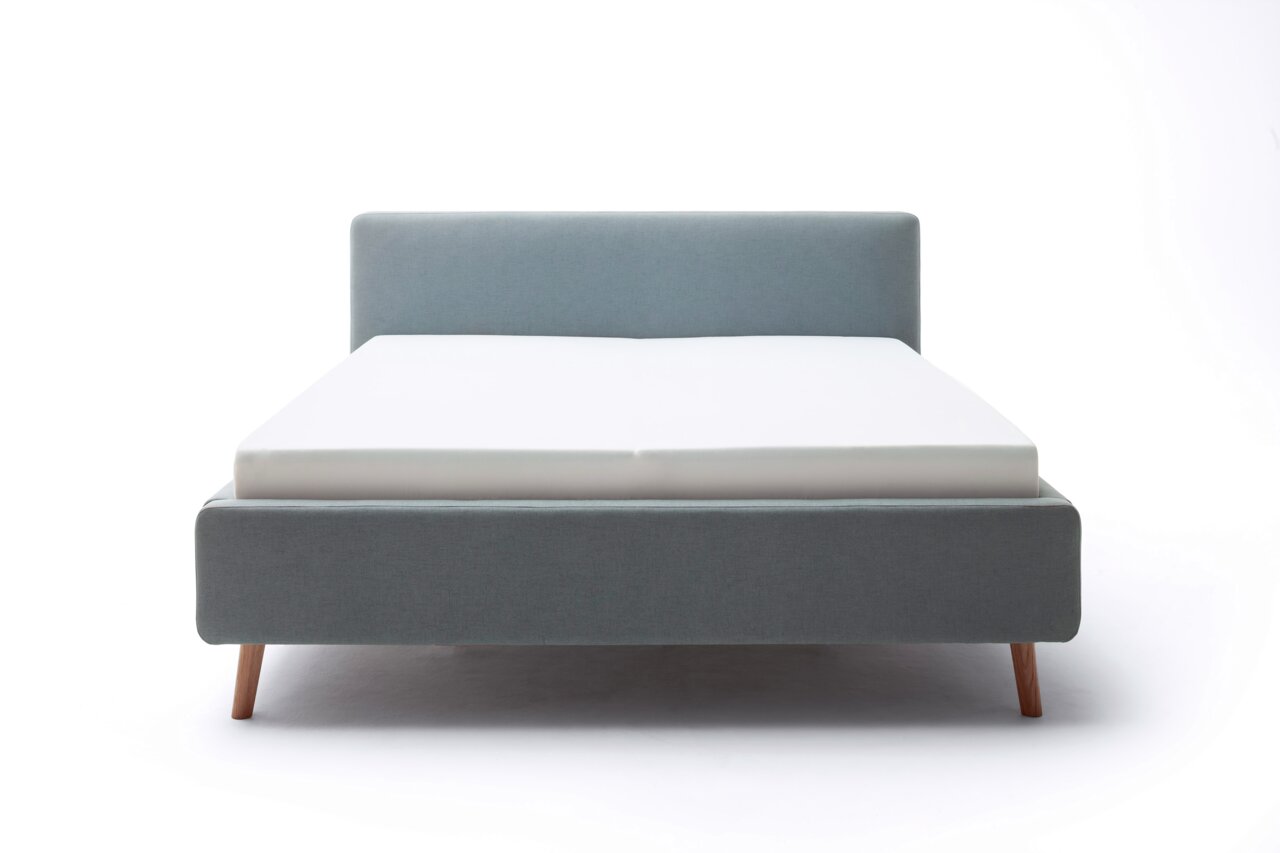 Frontale Ansicht eines grauen Polsterbetts mit Holzbeinen und weißer Matratze.
