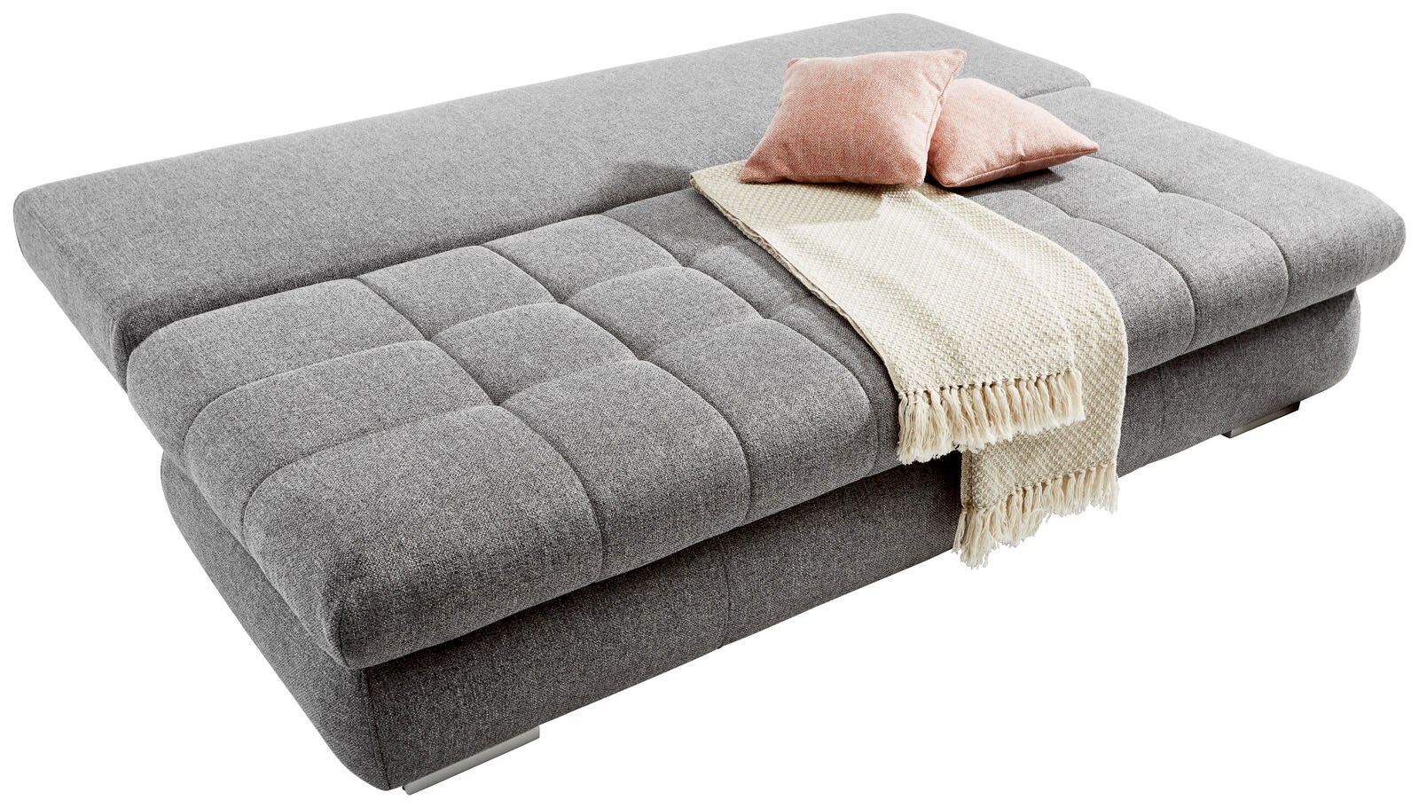 Graues Funktionssofa in Liegeposition mit zwei rosa Kissen und einer cremefarbenen Decke, seitliche Perspektive