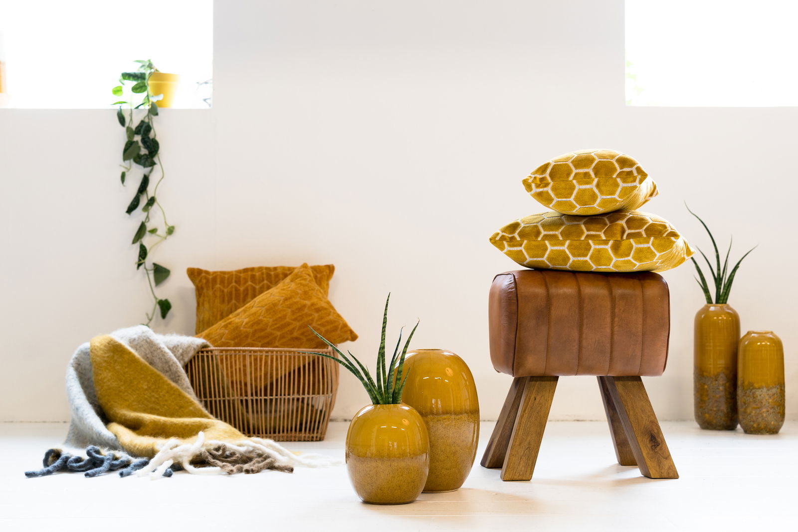 Light&Living Hocker RAMY Moderner Hocker aus braunem Leder mit Holzbeinen, im Vordergrund mit gelben Kissen und Vasen dekoriert, seitliche Perspektive.