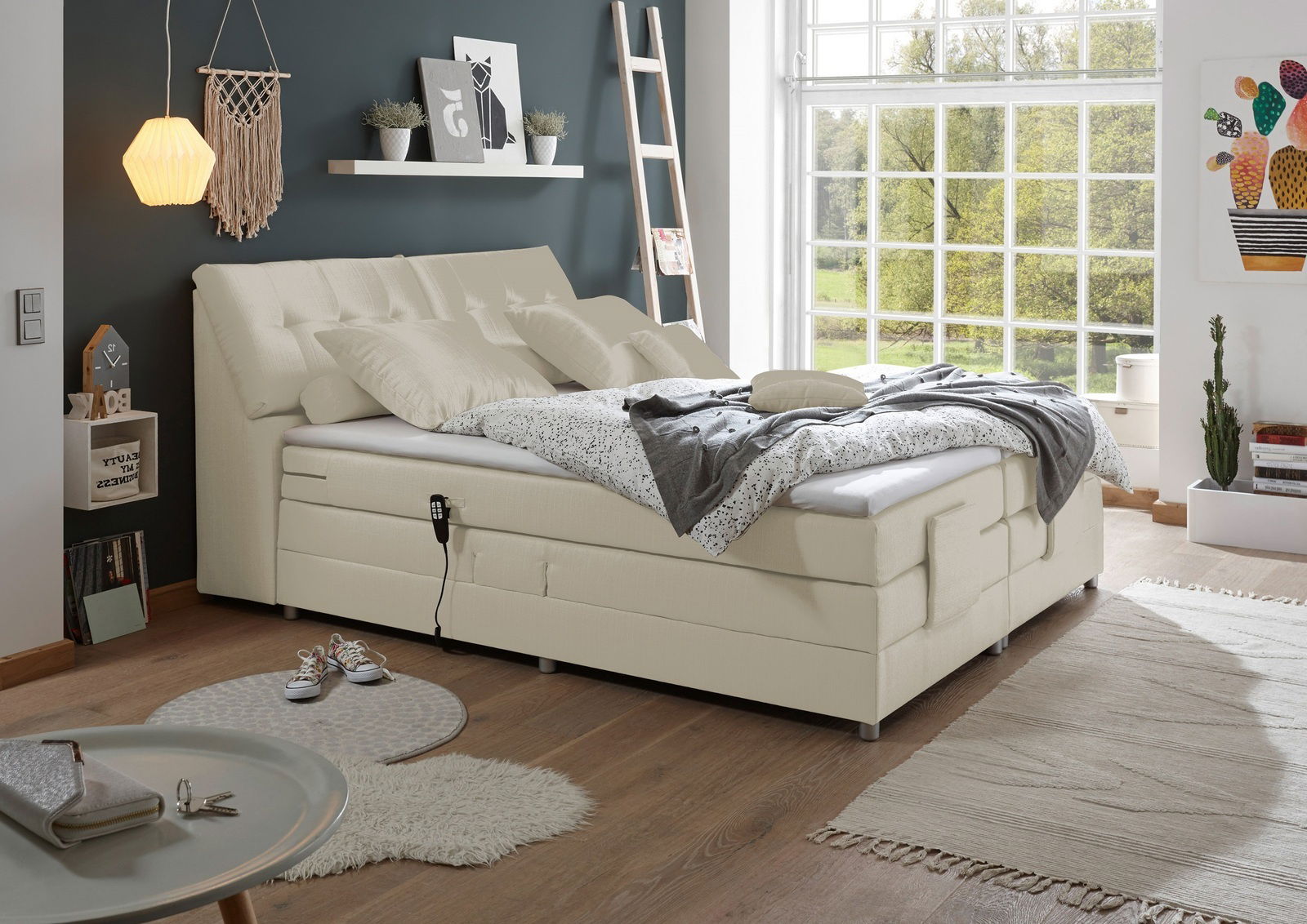 Boxspringbett in einem modernen Schlafzimmer mit großen Fenstern, seitliche Perspektive