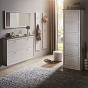 Moderne Garderobeneinrichtung mit weißem Schuhschrank, Spiegel und Garderobenpaneelen in einem hellen Raum mit Holzboden, seitliche Perspektive.