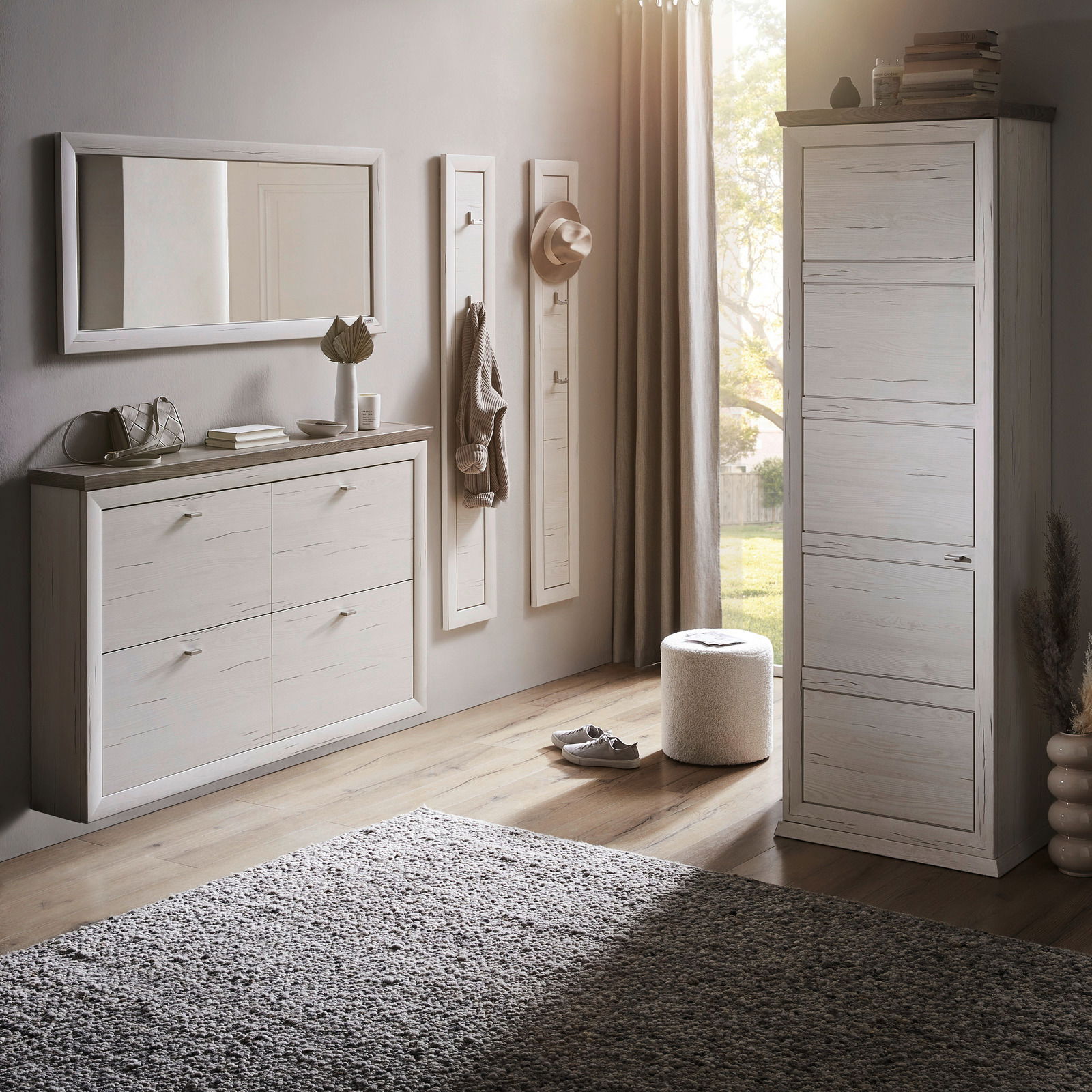 Moderne Garderobeneinrichtung mit weißem Schuhschrank, Spiegel und Garderobenpaneelen in einem hellen Raum mit Holzboden, seitliche Perspektive.