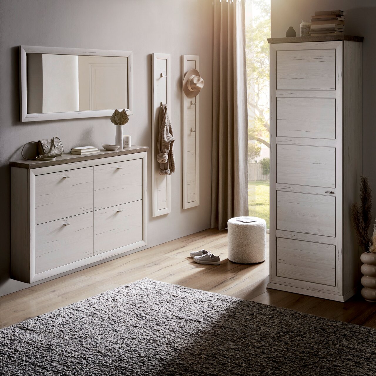 Moderne Garderobeneinrichtung mit weißem Schuhschrank, Spiegel und Garderobenpaneelen in einem hellen Raum mit Holzboden, seitliche Perspektive.