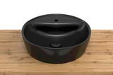 Schwarzes, rundes Waschbecken aus Keramik auf einer Holzoberfläche, Ansicht von oben.