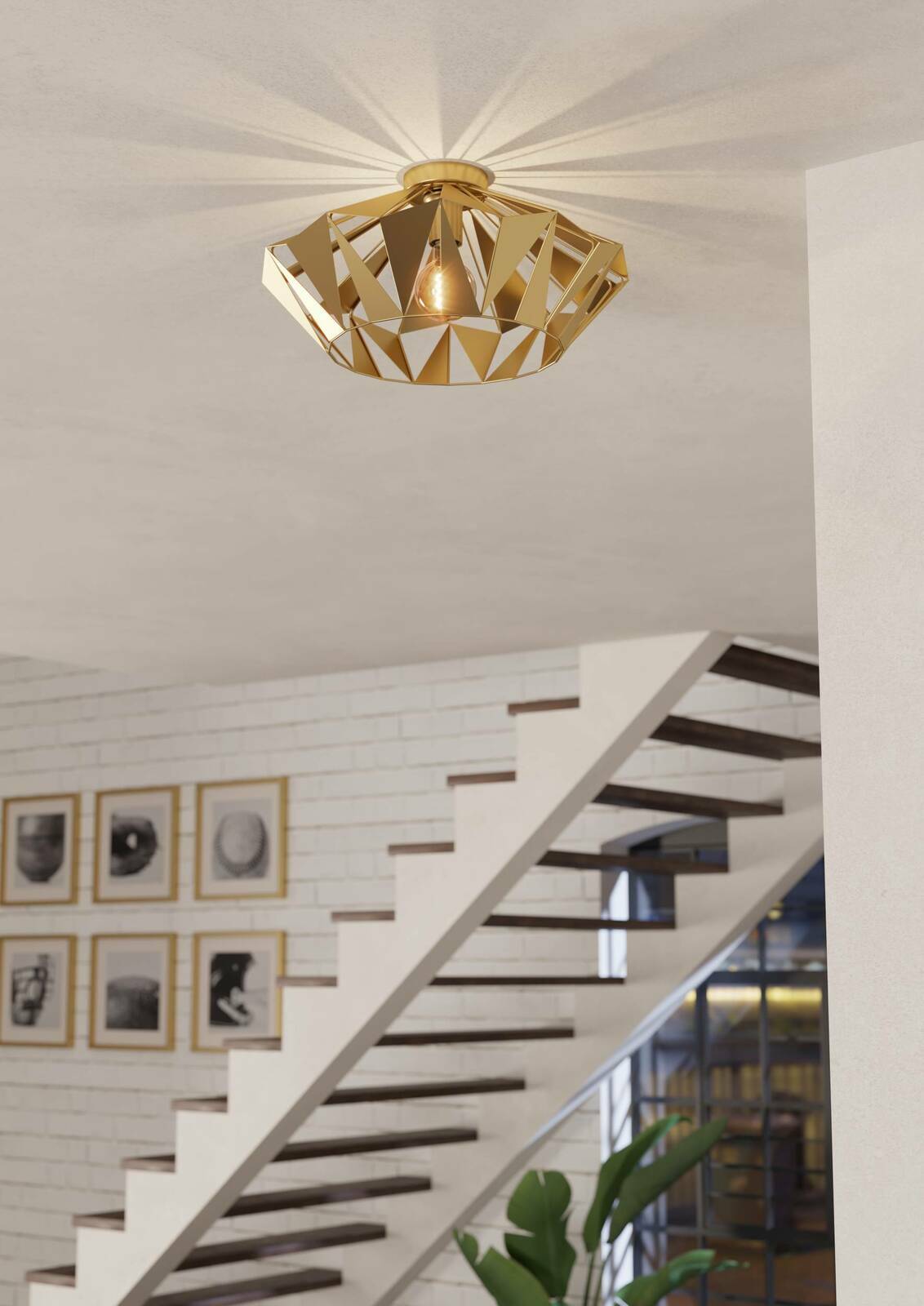 Goldene Deckenleuchte CARLTON in geometrischem Design, von unten betrachtet, montiert an einer weißen Decke in einem modernen Treppenhaus.