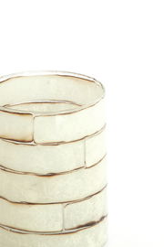 Nahaufnahme eines dekorativen Teelichthalters mit einem gestapelten, rechteckigen Design in sanften Weiß- und Beigetönen.