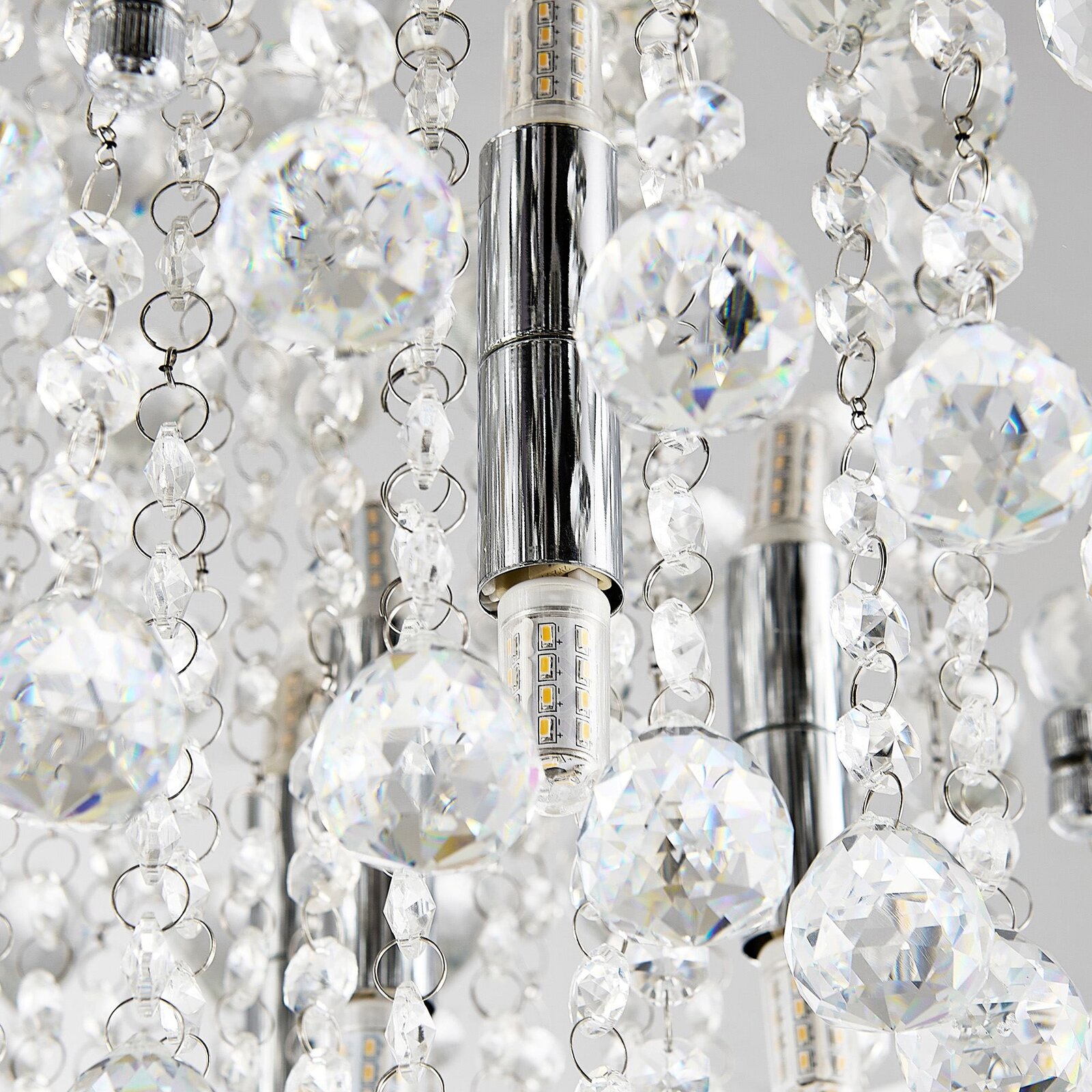 Nahaufnahme einer Deckenleuchte mit funkelnden Kristallanhängern und LED-Lampen, von unten betrachtet.