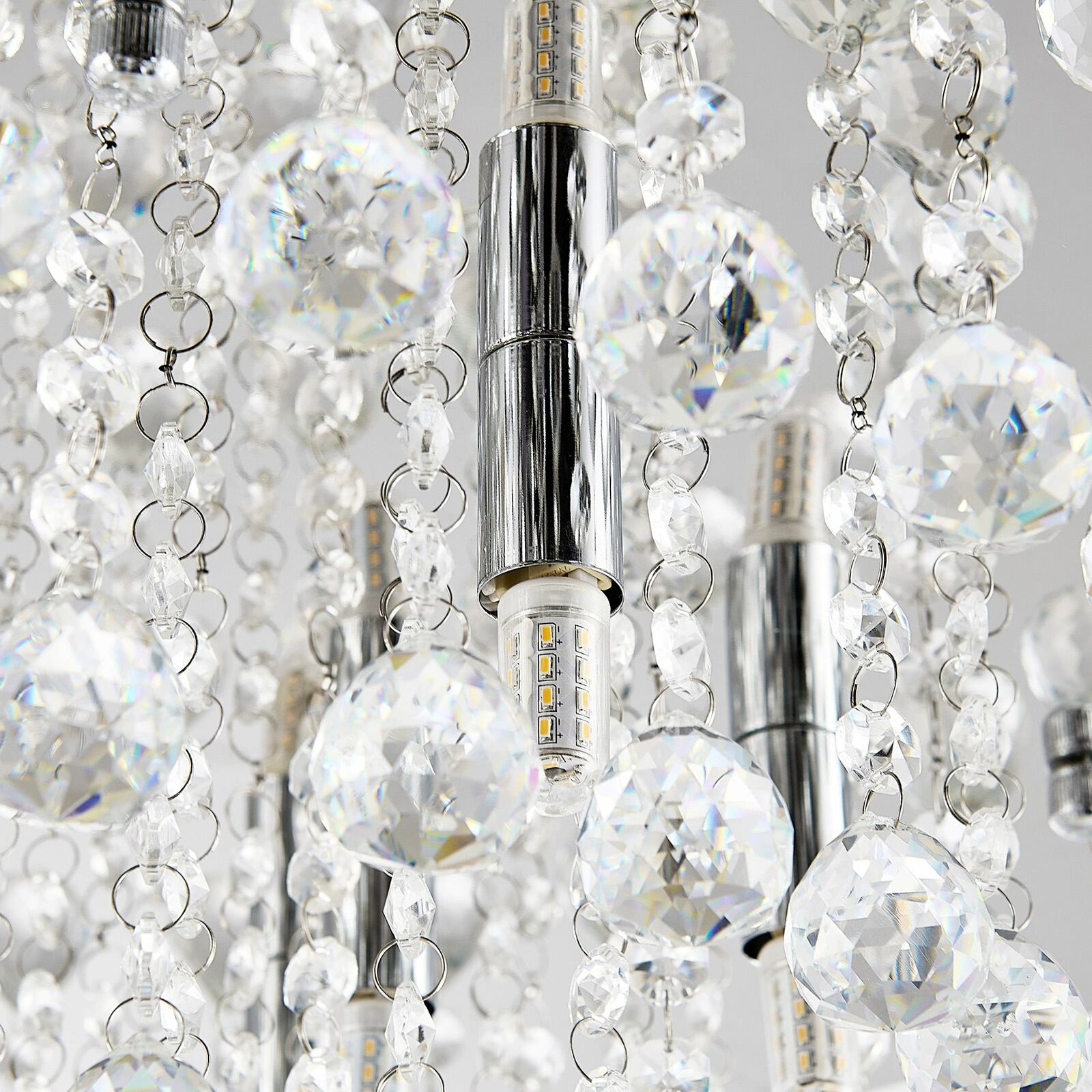 Nahaufnahme einer Deckenleuchte mit funkelnden Kristallanhängern und LED-Lampen, von unten betrachtet.