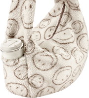 Flauschige Teddyfell-Umhängetasche in Creme mit braunem Smileys-Print und Reißverschluss, Seitenansicht schräg von vorn, mit seitlicher Außentasche und weißem Thermobecher