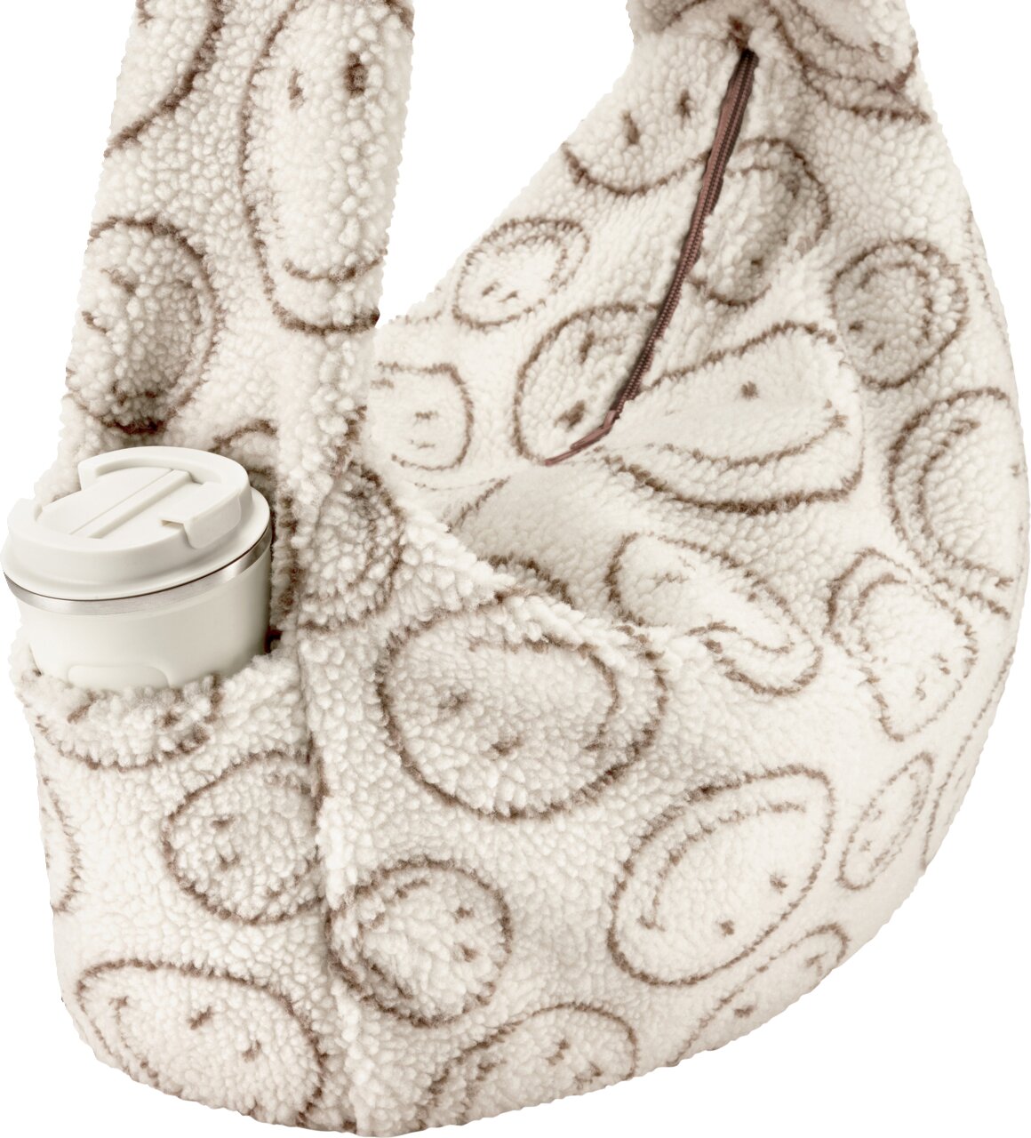 Flauschige Teddyfell-Umhängetasche in Creme mit braunem Smileys-Print und Reißverschluss, Seitenansicht schräg von vorn, mit seitlicher Außentasche und weißem Thermobecher