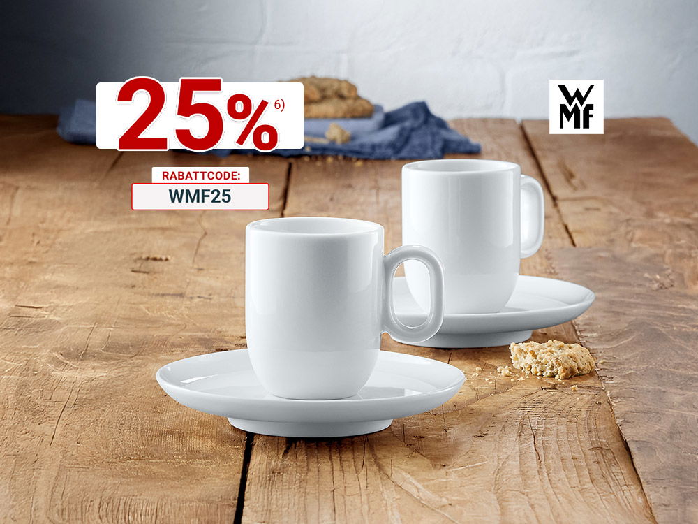 Zwei weiße WMF-Kaffeetassen mit Untertellern auf rustikalem Holztisch, umgeben von Kekskrümeln und Stoffserviette