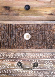 Detailansicht einer Kommodenfront mit verschiedenen Holzstrukturen und dekorativen Knöpfen.