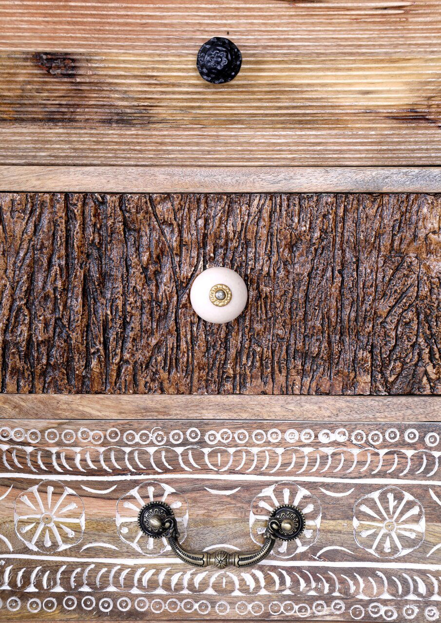 Detailansicht einer Kommodenfront mit verschiedenen Holzstrukturen und dekorativen Knöpfen.