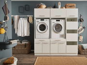 Hauswirtschaftsraum mit Waschmaschine und Trockner in einem modernen Schrank, umgeben von Körben und Wäscheleinen, aus der Frontalperspektive.