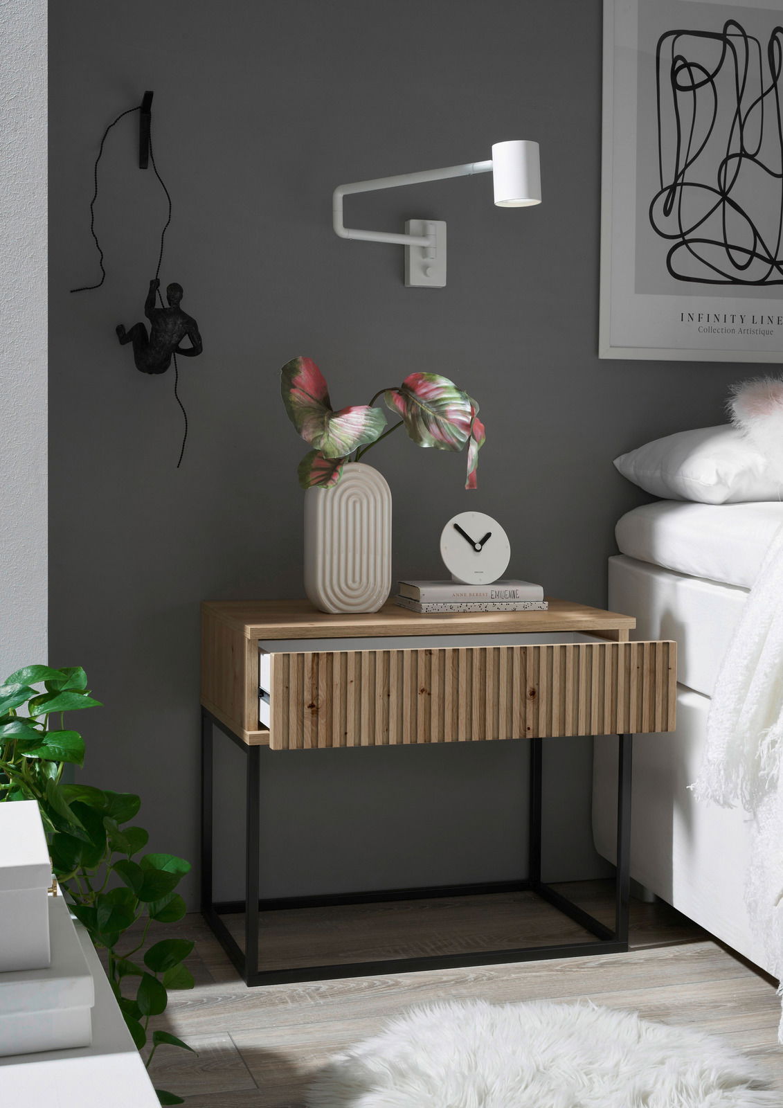 Moderne Nachtkommode aus Holz mit geriffelter Front und schwarzem Metallgestell, dekoriert mit einer Vase und einer Uhr, seitliche Perspektive.