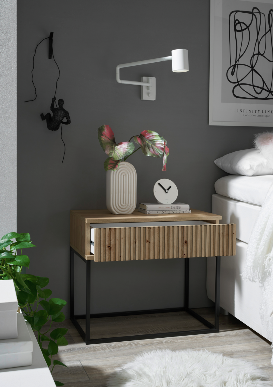 Moderne Nachtkommode aus Holz mit geriffelter Front und schwarzem Metallgestell, dekoriert mit einer Vase und einer Uhr, seitliche Perspektive.