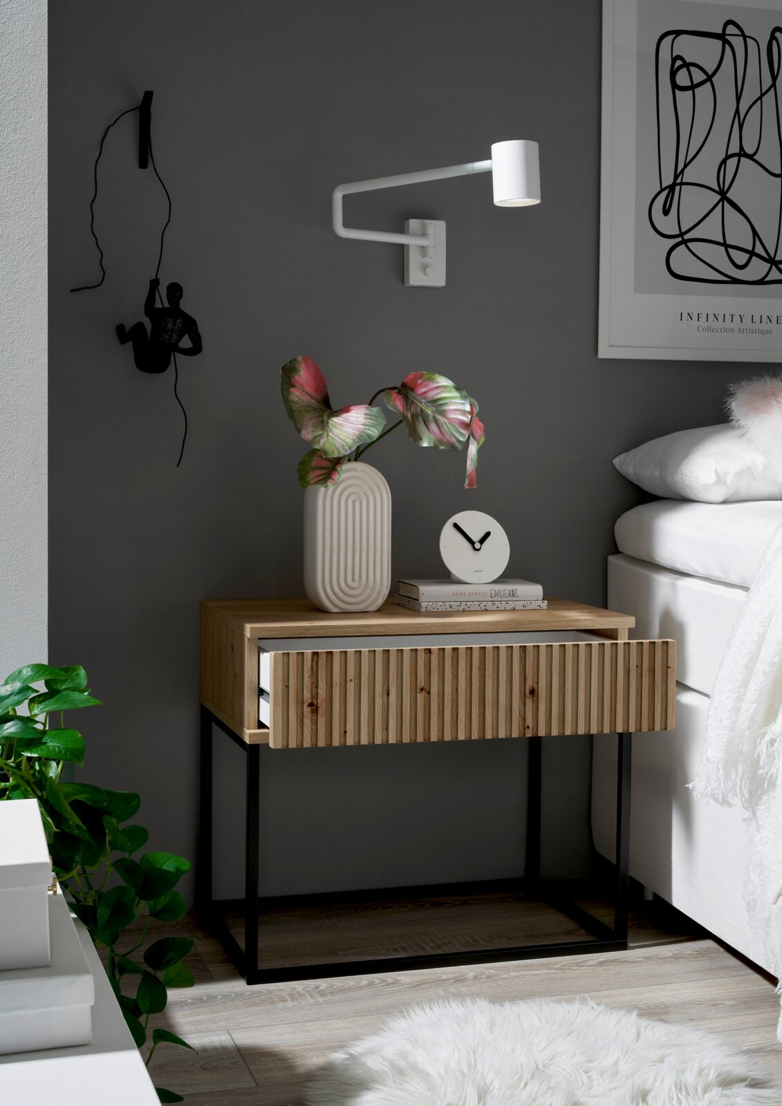 Moderne Nachtkommode aus Holz mit geriffelter Front und schwarzem Metallgestell, dekoriert mit einer Vase und einer Uhr, seitliche Perspektive.