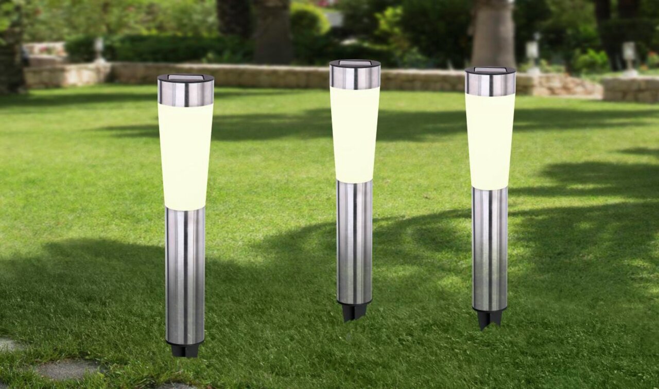 Drie moderne zonne-lampen van roestvrij staal in een tuin, gezien vanaf de voorkant.