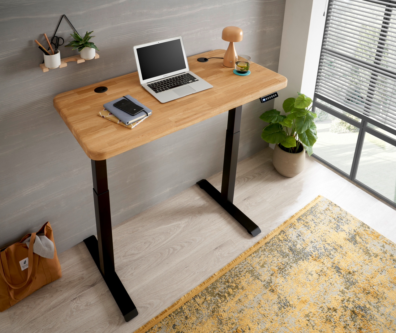 Moderner E-Schreibtisch mit Holzplatte und schwarzem Gestell, seitliche Perspektive, ausgestattet mit Laptop, Lampe und Pflanzen.