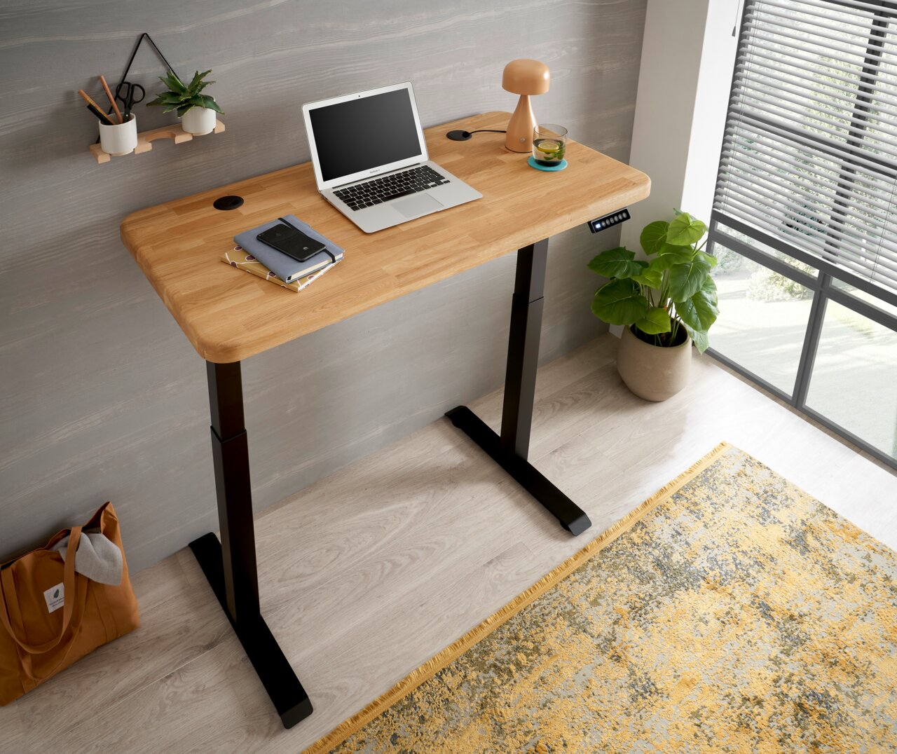 Moderner E-Schreibtisch mit Holzplatte und schwarzem Gestell, seitliche Perspektive, ausgestattet mit Laptop, Lampe und Pflanzen.