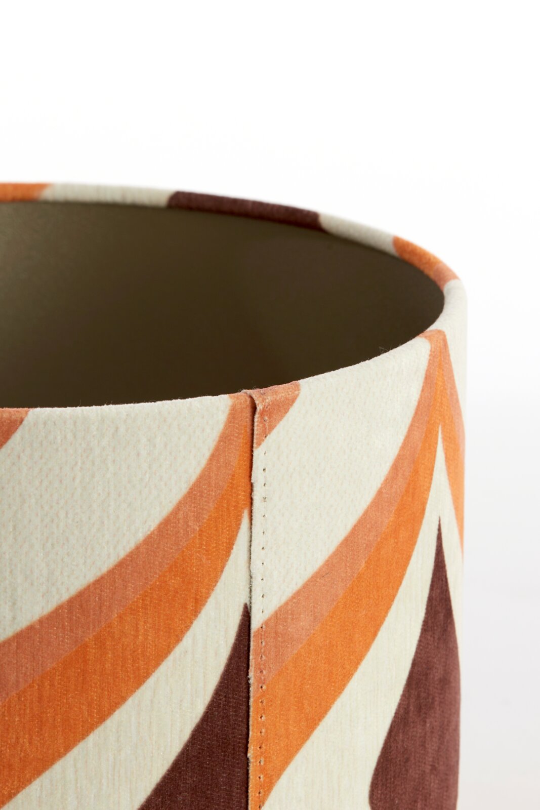 Close-up van een lampenkap met een geometrisch patroon in oranje- en bruintinten, zijaanzicht