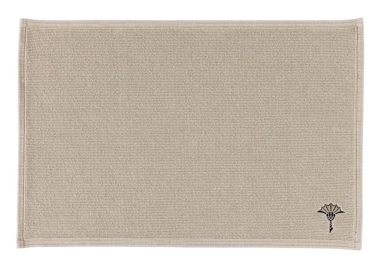 Beiger Badteppich 70 x 120 cm mit dezenter Struktur und einem kleinen, dekorativen Muster in der Ecke, Draufsicht.