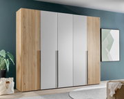 Moderne kledingkast met houten en witte elementen, gezien vanaf de voorkant, in een stijlvol ingerichte slaapkamer.