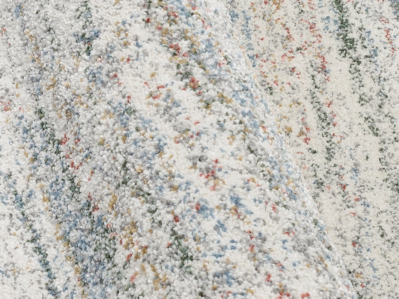 Nahaufnahme eines bunten Frisé-Teppichs mit gemusterten Streifen in verschiedenen Farben, aus seitlicher Perspektive aufgenommen.