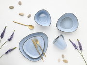 Hellblaues Keramik-Geschirrset mit Teller, Schalen und Tasse, kombiniert mit goldfarbenem Besteck auf weißem Hintergrund, Draufsicht von oben (Flatlay) mit Lavendelzweigen und dekorativen Steinen.