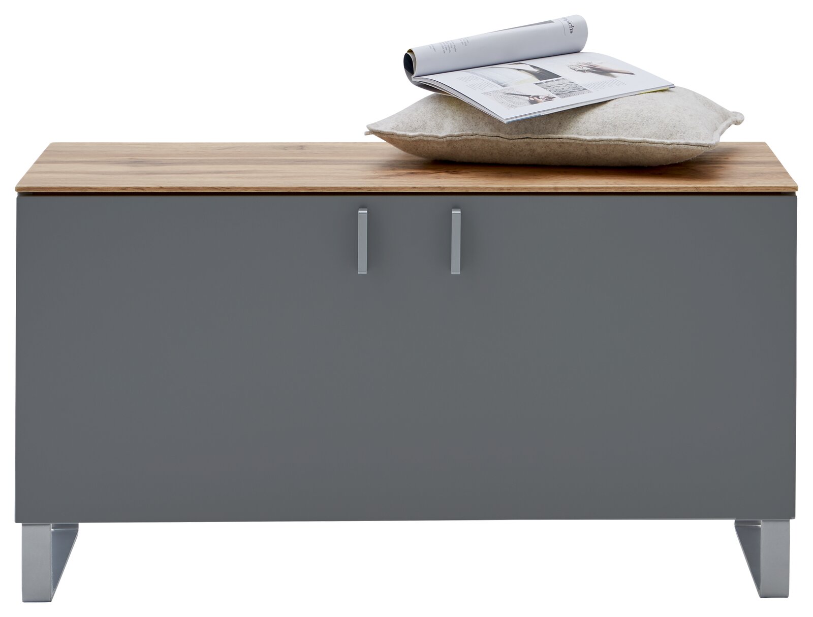 Garderobenbank mit grauer Front und Holzoberfläche, darauf ein Kissen und eine Zeitschrift, frontal betrachtet.