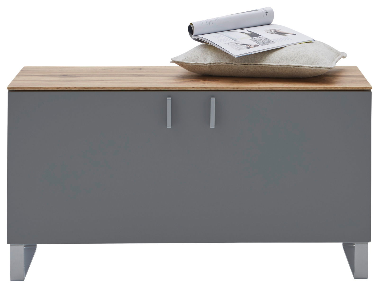 Garderobenbank mit grauer Front und Holzoberfläche, darauf ein Kissen und eine Zeitschrift, frontal betrachtet.