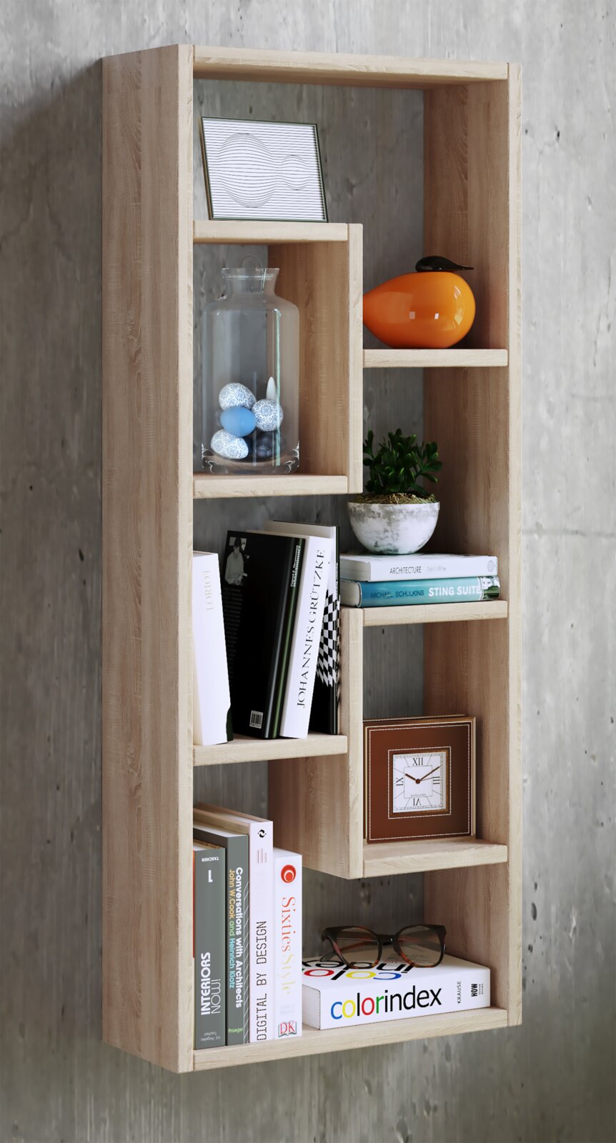 Modernes Wandregal aus hellem Holz mit versetzten Fächern, bestückt mit Büchern, Glasvase, kleiner Pflanze, Deko-Objekten und Uhr; fotografiert frontal in leichter Seitenperspektive vor grauer Betonwand.