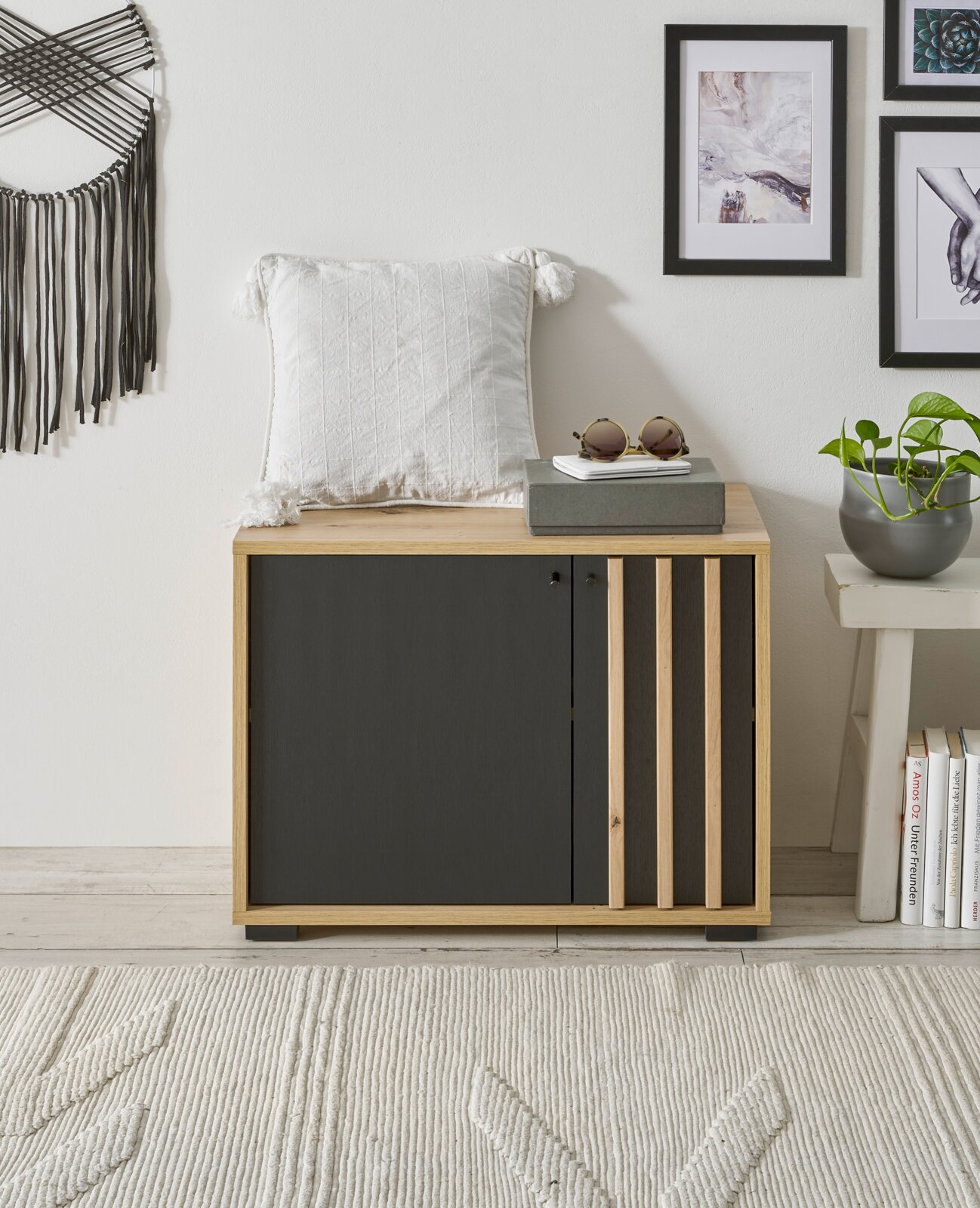 Garderobenbank aus Holz mit schwarzer Front, dekoriert mit einem weißen Kissen und Sonnenbrille, seitliche Perspektive
