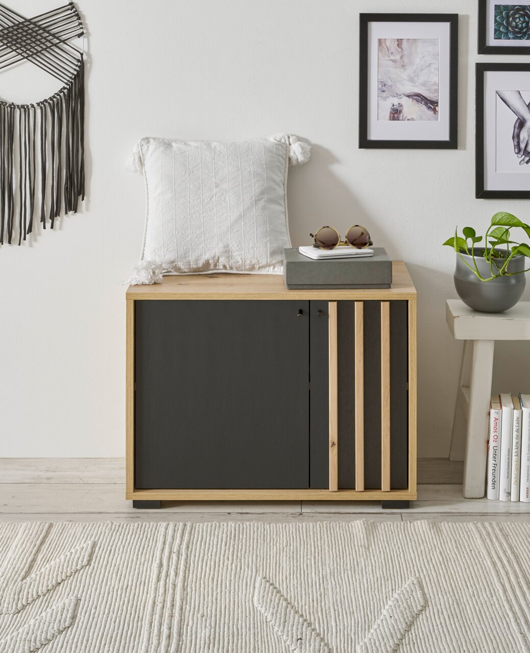 Garderobenbank aus Holz mit schwarzer Front, dekoriert mit einem weißen Kissen und Sonnenbrille, seitliche Perspektive