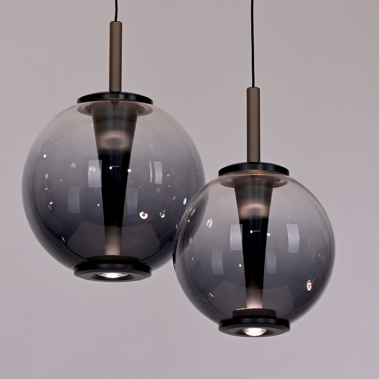 Zwei moderne LED-Pendelleuchten mit rauchgrauen Glaskugeln, von unten betrachtet.