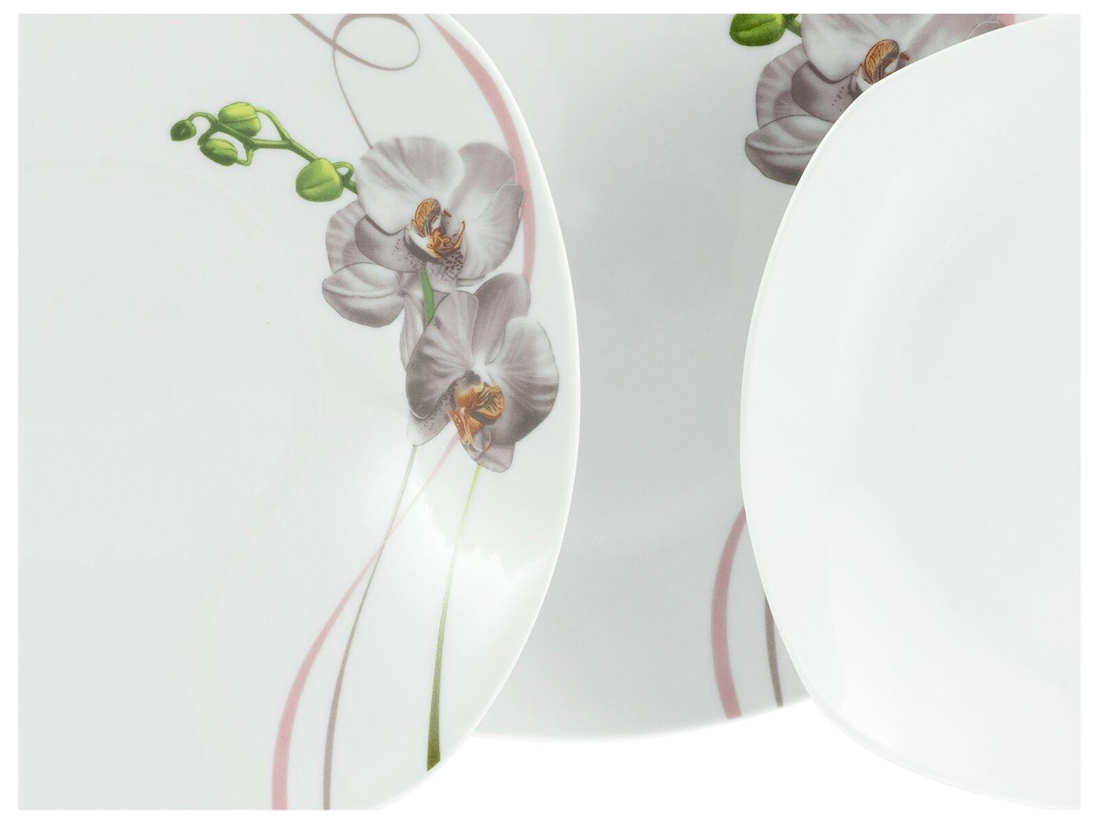 Drei weiße Porzellanteller mit Orchideen-Dekor und zarten Linien, fotografiert in leicht schräger Draufsicht