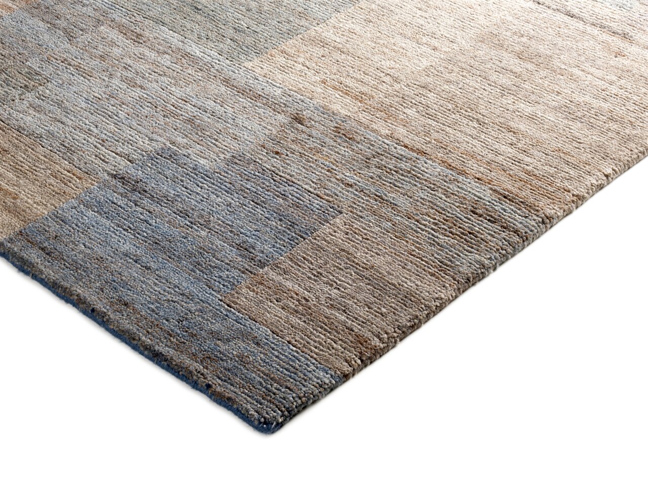 Nahaufnahme eines Wollteppichs in natürlichen Beige- und Blautönen, von der Seite fotografiert.