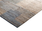 Nahaufnahme eines Wollteppichs in natürlichen Beige- und Blautönen, von der Seite fotografiert.