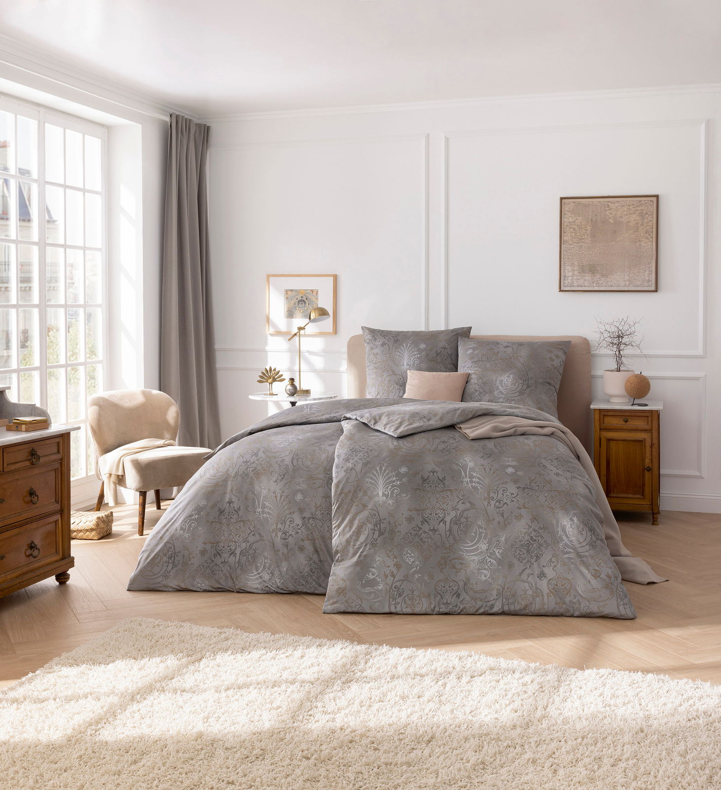 Elegante Bettwäsche in Grau mit floralem Muster, präsentiert in einem stilvoll eingerichteten Schlafzimmer mit Tageslicht von der Seite.